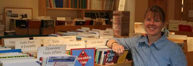 A smiling staff member with several boxes of music books